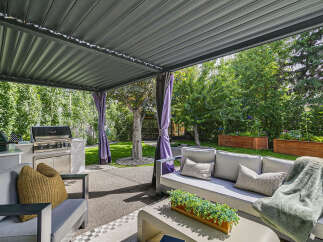 Enjoy outdoor living at its finest with this covered patio featuring a built-in grill station and comfortable seating.