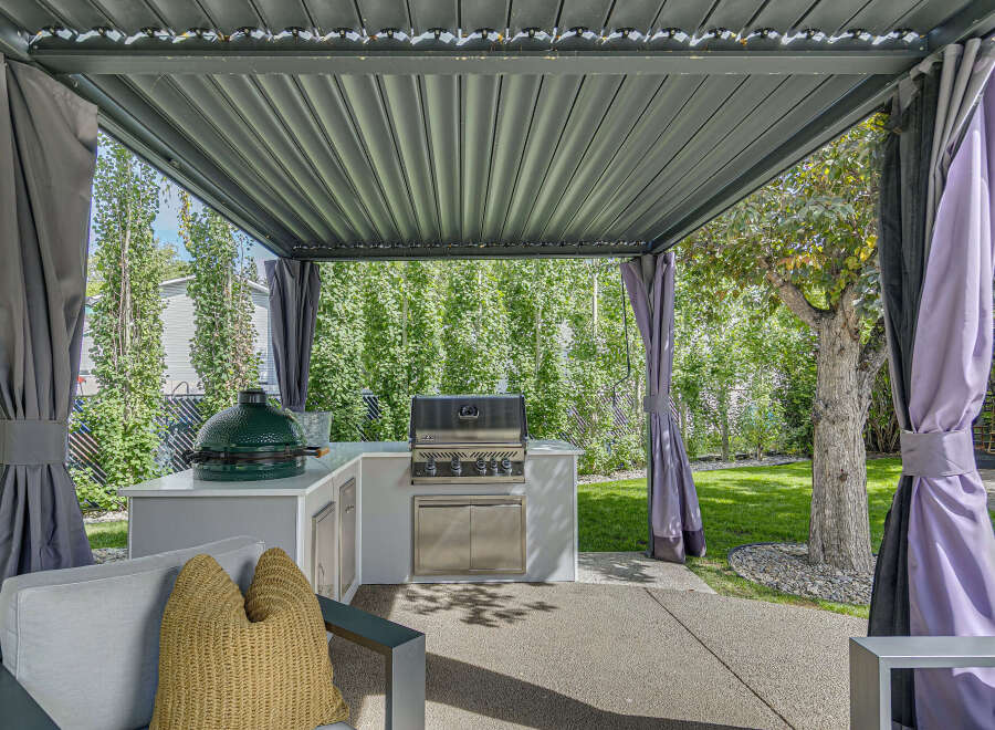 Experience outdoor living at its finest with this covered patio featuring a built-in grill and a large green egg smoker.
