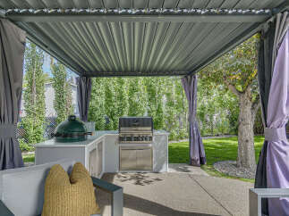 Experience outdoor living at its finest with this covered patio featuring a built-in grill and a large green egg smoker.