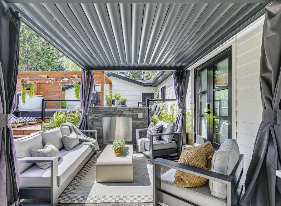 Experience luxurious outdoor living with this stunning covered patio, featuring a built-in stone fireplace and comfortable seating.
