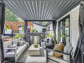 Experience luxurious outdoor living with this stunning covered patio, featuring a built-in stone fireplace and comfortable seating.