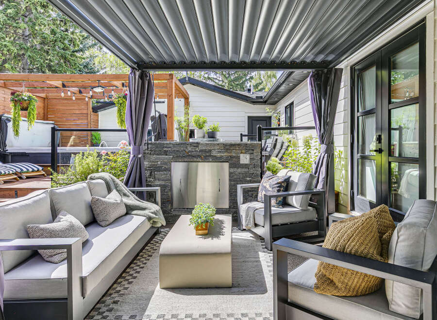 Enjoy outdoor living at its finest with this covered patio featuring a sleek outdoor kitchen and comfortable seating area.