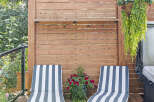 Relax and unwind on this beautiful wooden deck, featuring two comfortable striped lounge chairs perfect for soaking up the sun.