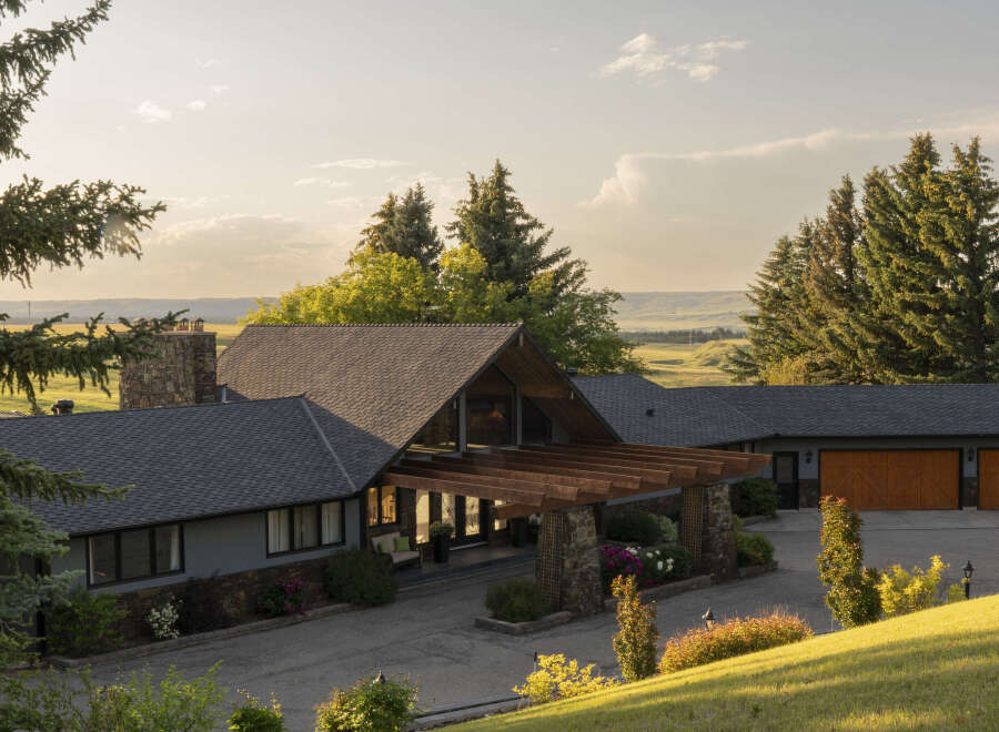 Discover this stunning property featuring a modern home with a striking stone chimney and a welcoming wooden pergola entrance.