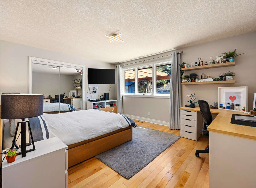 This modern bedroom features a comfortable bed with a wooden frame and a stylish striped duvet.