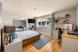 This modern bedroom features a comfortable bed with a wooden frame and a stylish striped duvet.