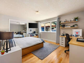 This modern bedroom features a comfortable bed with a wooden frame and a stylish striped duvet.