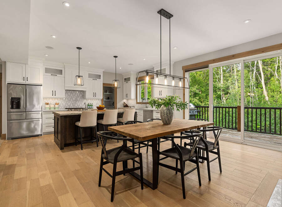 Experience modern living in this stunning kitchen and dining area, featuring sleek white cabinetry, a spacious island with bar seating, and a beautiful wooden dining table perfect for gatherings.