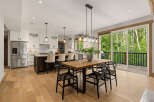 Experience modern living in this stunning kitchen and dining area, featuring sleek white cabinetry, a spacious island with bar seating, and a beautiful wooden dining table perfect for gatherings.