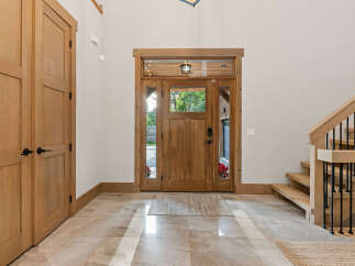 Step into this inviting entryway featuring a beautiful wooden double door with glass panels, allowing natural light to flood the space.