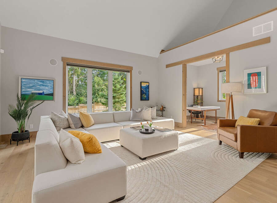 Experience modern living in this spacious living room featuring a large sectional sofa and a cozy leather armchair.