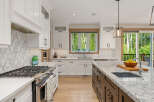 Experience luxury in this stunning modern kitchen, featuring sleek white cabinetry, a decorative tile backsplash, and a large granite island perfect for entertaining.