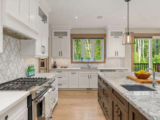 Experience luxury in this stunning modern kitchen, featuring sleek white cabinetry, a decorative tile backsplash, and a large granite island perfect for entertaining.
