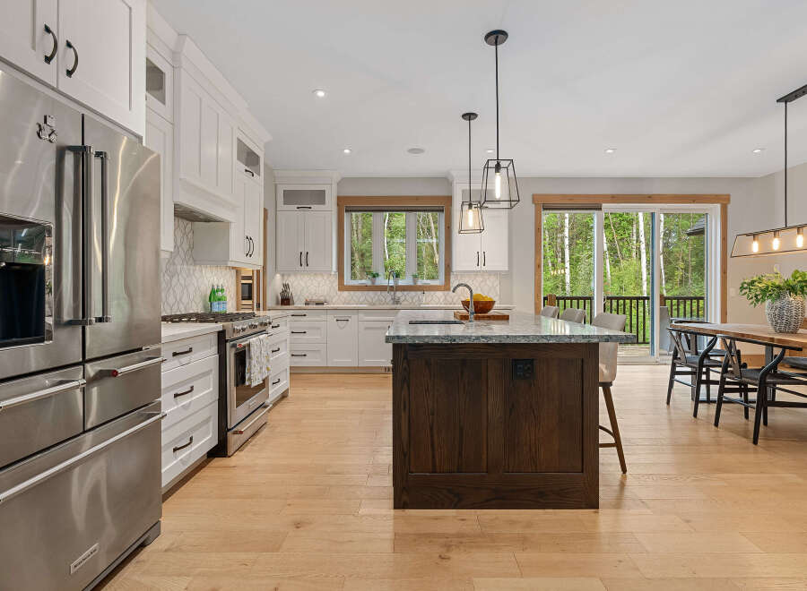 Experience modern luxury in this stunning kitchen, featuring a spacious island with a granite countertop and rich wood cabinetry.