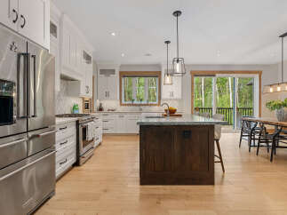 Experience modern luxury in this stunning kitchen, featuring a spacious island with a granite countertop and rich wood cabinetry.