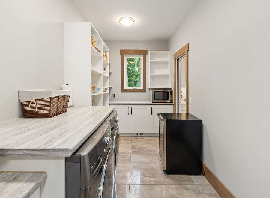 Discover this spacious laundry room featuring a sleek LG washer and dryer set, complemented by a stylish marble-patterned countertop.