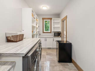 Discover this spacious laundry room featuring a sleek LG washer and dryer set, complemented by a stylish marble-patterned countertop.