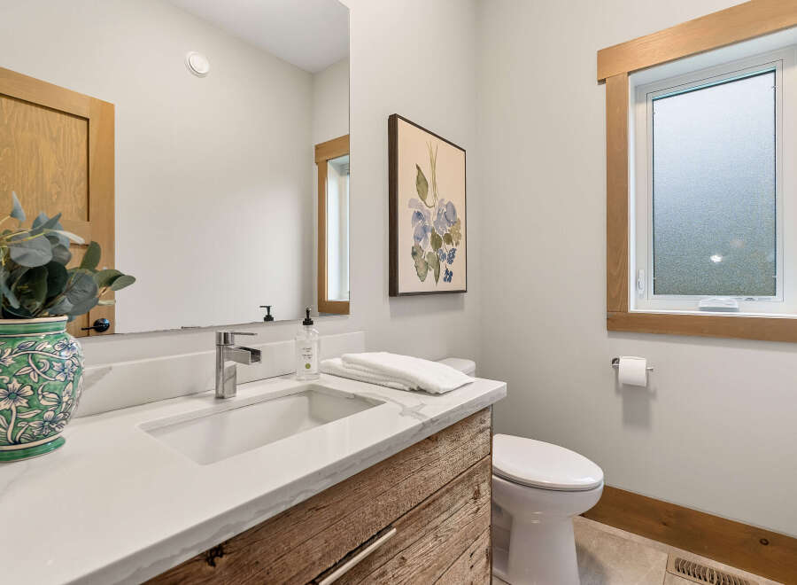 This modern bathroom features a sleek vanity with a quartz countertop and a rustic wood cabinet.