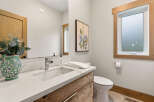 This modern bathroom features a sleek vanity with a quartz countertop and a rustic wood cabinet.