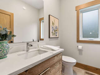 This modern bathroom features a sleek vanity with a quartz countertop and a rustic wood cabinet.