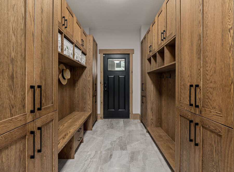 This spacious mudroom features custom oak cabinetry with ample storage and a built-in bench for convenience.