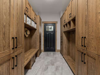 This spacious mudroom features custom oak cabinetry with ample storage and a built-in bench for convenience.