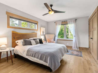 Experience serene comfort in this inviting bedroom, featuring a plush king-sized bed adorned with soft linens and decorative pillows.
