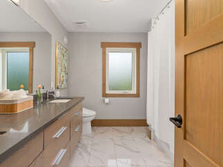 Experience modern comfort in this beautifully appointed bathroom, featuring a sleek vanity with ample storage and a stylish quartz countertop.