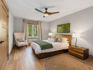 Experience serene living in this beautifully appointed bedroom, featuring a plush armchair and a large window offering picturesque views of lush greenery.