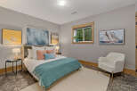 This serene bedroom offers a tranquil retreat with its calming gray walls and comfortable queen-size bed adorned with plush pillows and a cozy teal throw.