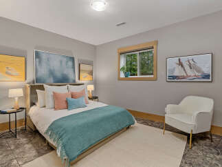 This serene bedroom offers a tranquil retreat with its calming gray walls and comfortable queen-size bed adorned with plush pillows and a cozy teal throw.