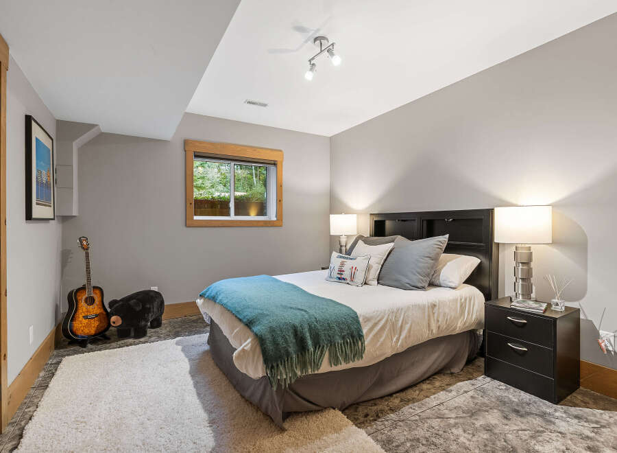 This charming bedroom features a comfortable queen-size bed adorned with a teal throw blanket and decorative pillows.