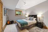This charming bedroom features a comfortable queen-size bed adorned with a teal throw blanket and decorative pillows.