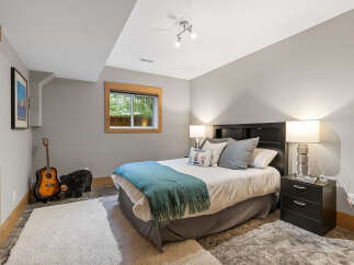 This charming bedroom features a comfortable queen-size bed adorned with a teal throw blanket and decorative pillows.