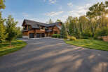 Experience luxury living in this stunning custom-built home, featuring a warm wood exterior and a spacious three-car garage.