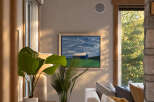 This living room features a modern aesthetic with a large abstract painting of a blue barn and sky above a white sofa.