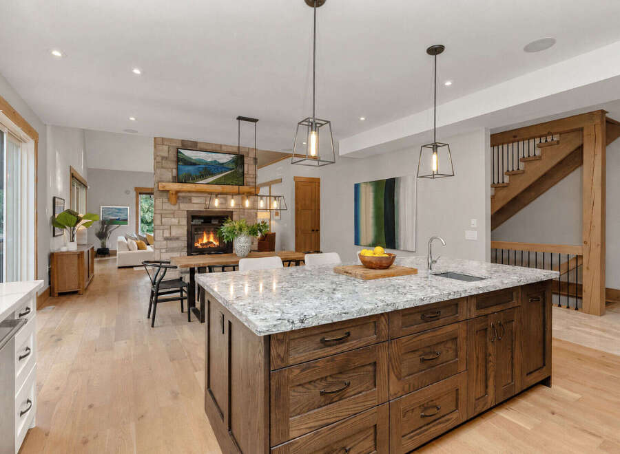 Experience modern living in this stunning open-concept kitchen and living area, featuring a cozy stone fireplace and a spacious island perfect for entertaining.