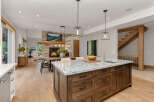 Experience modern living in this stunning open-concept kitchen and living area, featuring a cozy stone fireplace and a spacious island perfect for entertaining.
