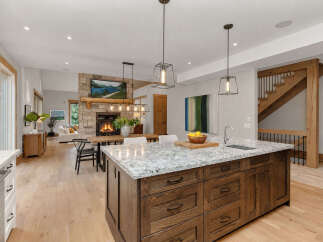 Experience modern living in this stunning open-concept kitchen and living area, featuring a cozy stone fireplace and a spacious island perfect for entertaining.