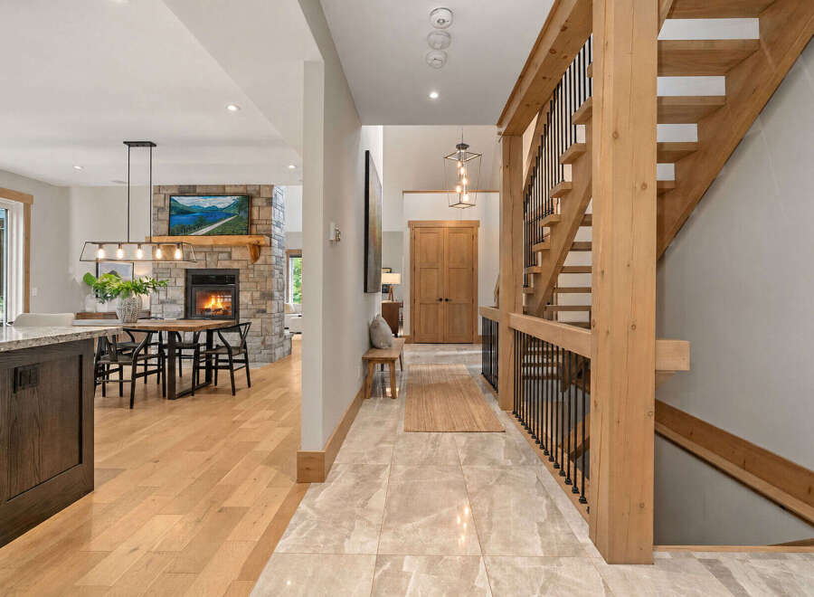 Experience rustic elegance in this stunning home featuring a grand wooden staircase and a cozy stone fireplace.