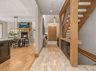 Experience rustic elegance in this stunning home featuring a grand wooden staircase and a cozy stone fireplace.