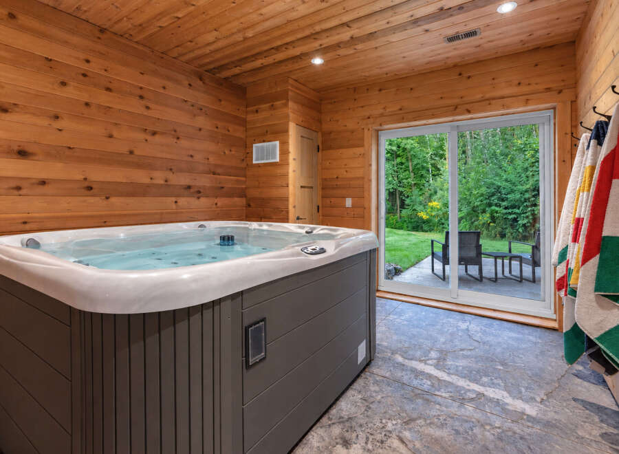 Indulge in relaxation in this luxurious indoor hot tub room, featuring warm wood paneling and a spacious jacuzzi.
