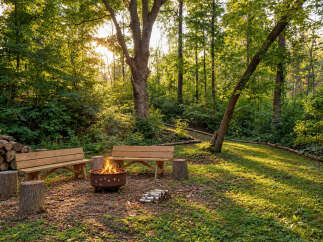 Experience the perfect outdoor retreat with this inviting fire pit area, nestled within a serene wooded landscape.
