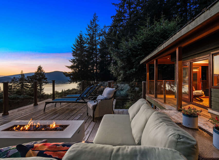 Experience breathtaking sunset views from this stunning deck, complete with a modern fire pit and comfortable seating.
