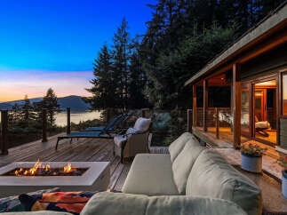 Experience breathtaking sunset views from this stunning deck, complete with a modern fire pit and comfortable seating.