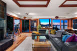 Experience breathtaking sunset views from this stunning living room, featuring a sleek black leather sectional and a glass coffee table.