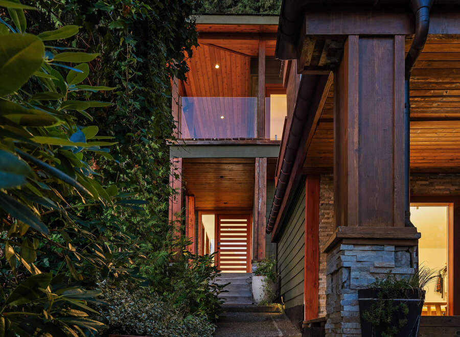 Experience modern luxury in this stunning home featuring a striking wood-paneled exterior and a welcoming entryway with a sleek horizontal-slat door.