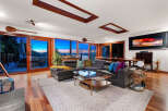 Experience breathtaking sunset views from this stunning living room, featuring expansive windows that open to a serene waterfront landscape.