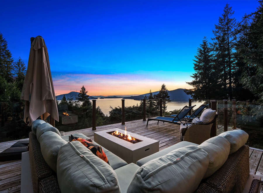 Experience breathtaking sunset views from this stunning deck, complete with a modern fire pit and comfortable seating.