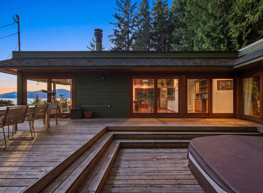 Enjoy breathtaking sunset views from this expansive wooden deck, complete with an outdoor dining area and a relaxing hot tub.